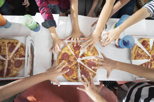Kinderhände, die nach einer Pizza auf dem Tisch greifen - RNF01381
