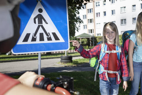 Smiling boy pointing at pedestrian sign - RNF01389