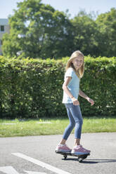 Smiling blond girl skateboarding on traffic course - RNF01398
