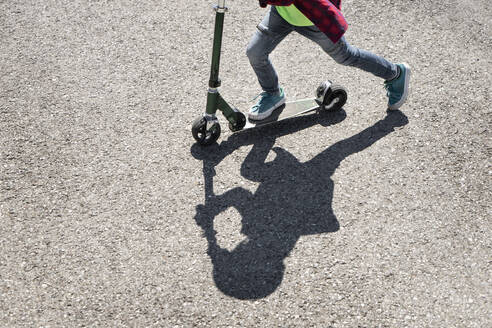 Boy riding push scooter on road - RNF01400