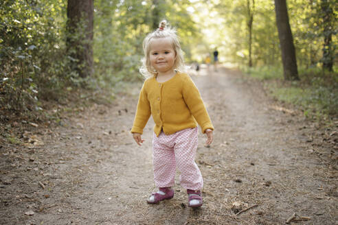 Lächelndes süßes blondes Mädchen auf Fußweg im Wald - DWF00574