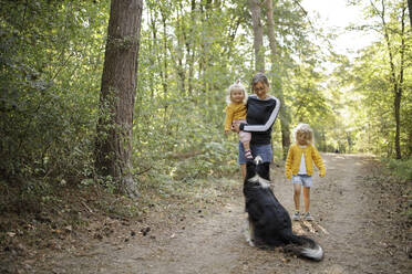 Woman with daughters and dog in forest - DWF00577