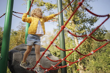 Girl playing on jungle gym at playground - DWF00580