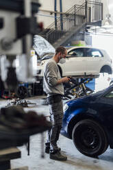 Mechanic using mobile phone in auto repair workshop - PGF01101