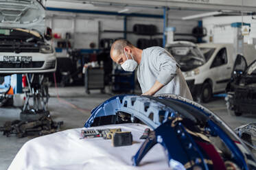 Automechaniker bei der Analyse einer Stoßstange in der Werkstatt - PGF01112