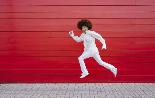 Afro-Frau springt durch rote Wand - GIOF15501