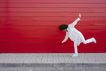 Playful woman balancing on one leg over footpath - GIOF15508