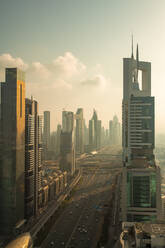 United Arab Emirates, Dubai, Sheikh Zayed Road stretching between tall downtown skyscrapers at sunset - TAMF03395