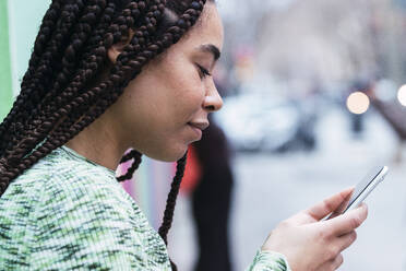 Smiling woman with braided hair using smart phone - PNAF03901