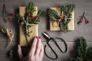 Hand einer Frau, die natürlich verpackte Weihnachtsgeschenke vorbereitet - EVGF04007