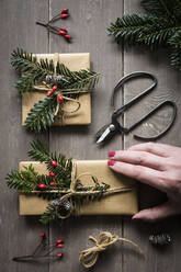 Hand einer Frau, die natürlich verpackte Weihnachtsgeschenke vorbereitet - EVGF04011