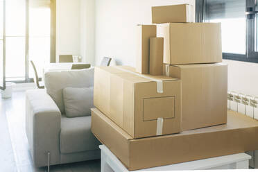 Cardboard boxes arranged on coffee table by sofa in living room at home - EGHF00397