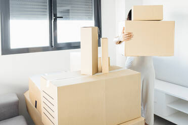 Woman carrying cardboard boxes at new home - EGHF00400