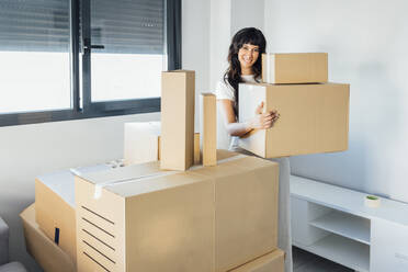 Smiling woman with cardboard boxes at new home - EGHF00401