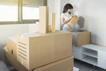 Woman unpacking cardboard boxes at new home - EGHF00405