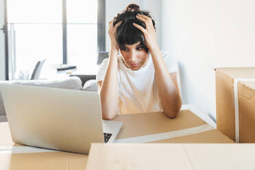 Frustrated woman looking at laptop at new home - EGHF00418