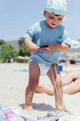 Niedlicher Junge mit Smartphone im Sand am Strand stehend - PGF01118