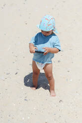 Junge mit Smartphone im Sand am Strand stehend - PGF01120