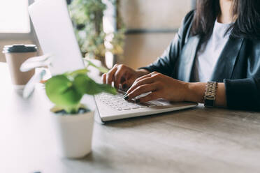 Geschäftsfrau arbeitet am Laptop am Schreibtisch im Büro - MEUF06040