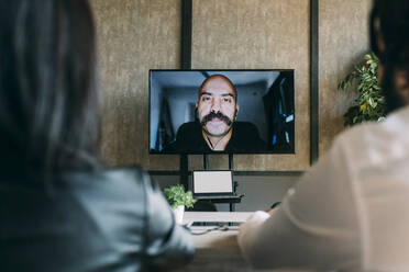 Geschäftsleute bei einem Videoanruf mit einem Kollegen in einer Besprechung am Arbeitsplatz - MEUF06067