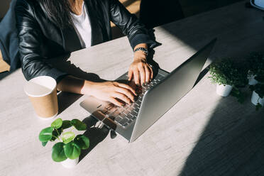 Businesswoman typing on laptop at desk in office - MEUF06093