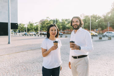 Business colleagues having coffee on footpath in city - MEUF06113