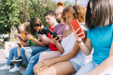 Multirassische Freunde benutzen Mobiltelefone an einem sonnigen Tag - MEUF06120