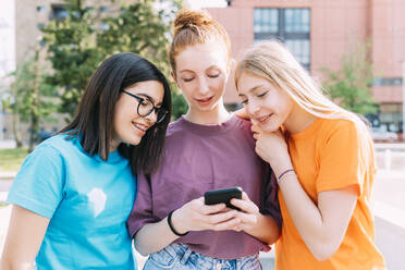 Teenager-Mädchen teilt Smartphone mit Freunden - MEUF06138