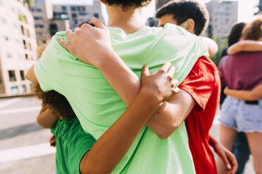 Multirassische Freunde umarmen sich auf dem Fußweg stehend - MEUF06150