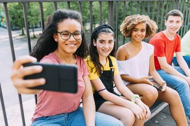 Glückliche junge Frau nimmt Selfie mit Freunden durch Smartphone - MEUF06174