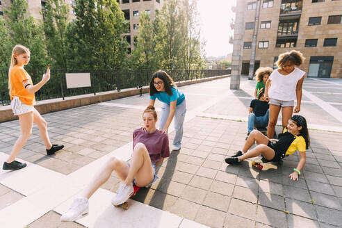 Mädchen skateboarden mit Freunden auf einem Parkplatz - MEUF06202
