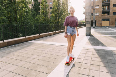 Teenage girl skateboarding on sunny day - MEUF06204