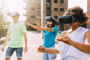 Multirassische Freunde tragen Virtual-Reality-Simulator an einem sonnigen Tag - MEUF06209