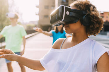 Mädchen trägt Virtual-Reality-Simulator an einem sonnigen Tag - MEUF06210