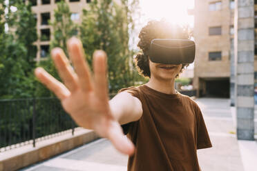 Lächelnder Junge im Virtual-Reality-Simulator gestikuliert - MEUF06223