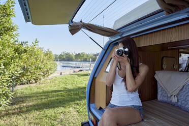 Woman photographing through camera in motor home - FMOF01480