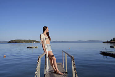 Lächelnde Frau steht auf einem Steg über dem See - FMOF01481