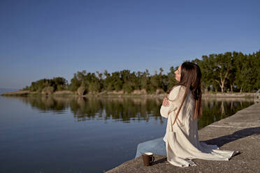 Junge Frau, die sich auf einem Steg am See umarmt - FMOF01486