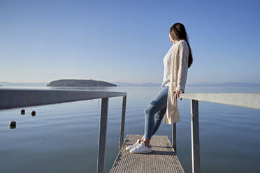Junge Frau steht auf einem Steg über dem See - FMOF01491