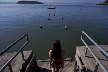 Junge Frau im Bikini geht an einem sonnigen Tag zum See - FMOF01503