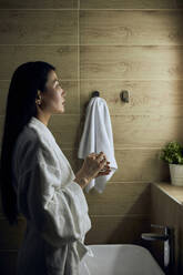 Woman wearing bathrobe doing skincare routine - DSHF00489