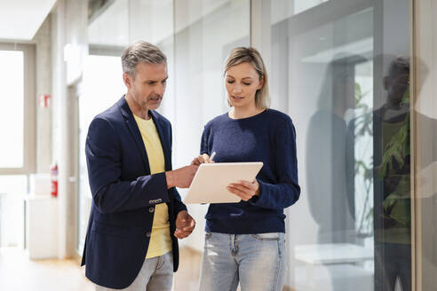 Businessman and businesswoman sharing digital tablet in office - DIGF17921