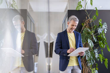 Älterer Geschäftsmann benutzt digitales Tablet im Büro - DIGF17922