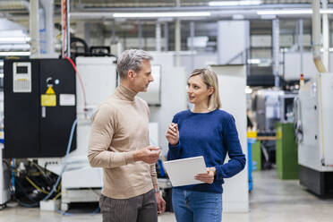 Businessman and businesswoman with digital tablet talking in factory - DIGF17943