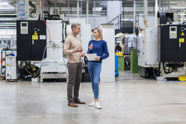 Businessman and businesswoman with digital tablet talking in factory - DIGF17945