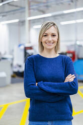 Porträt einer lächelnden Geschäftsfrau in einer Fabrik - DIGF17974