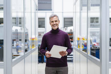 Portrait of smiling businessman holding digital tablet in factory - DIGF17983