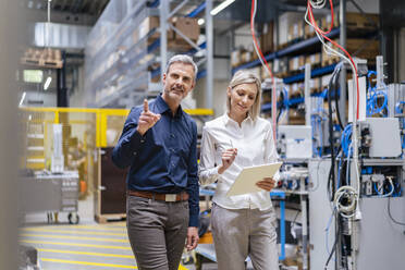 Businessman and businesswoman with digital tablet talking in factory - DIGF17989