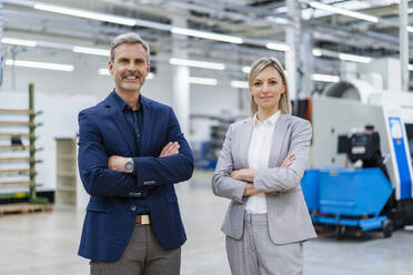 Portrait of confident businessman and businesswoman in factory - DIGF18025