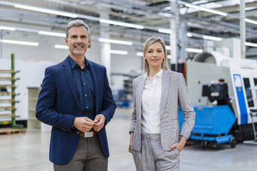 Portrait of confident businessman and businesswoman in factory - DIGF18026